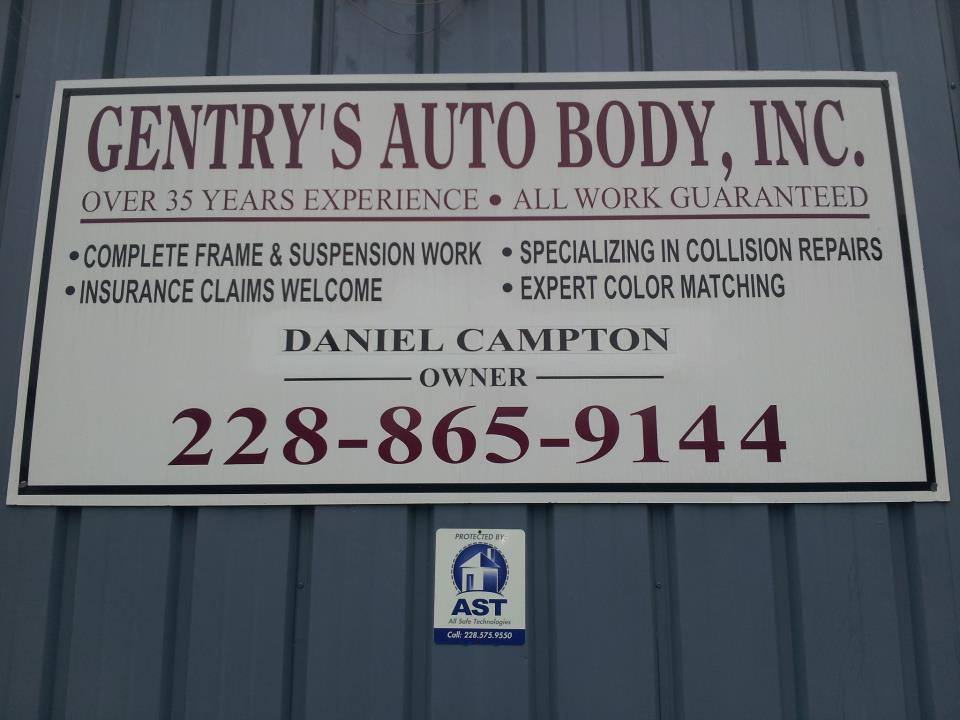 White shop sign with maroon lettering on grey metal siding, listing frame & suspension work, collision repairs, insurance claims and color matching